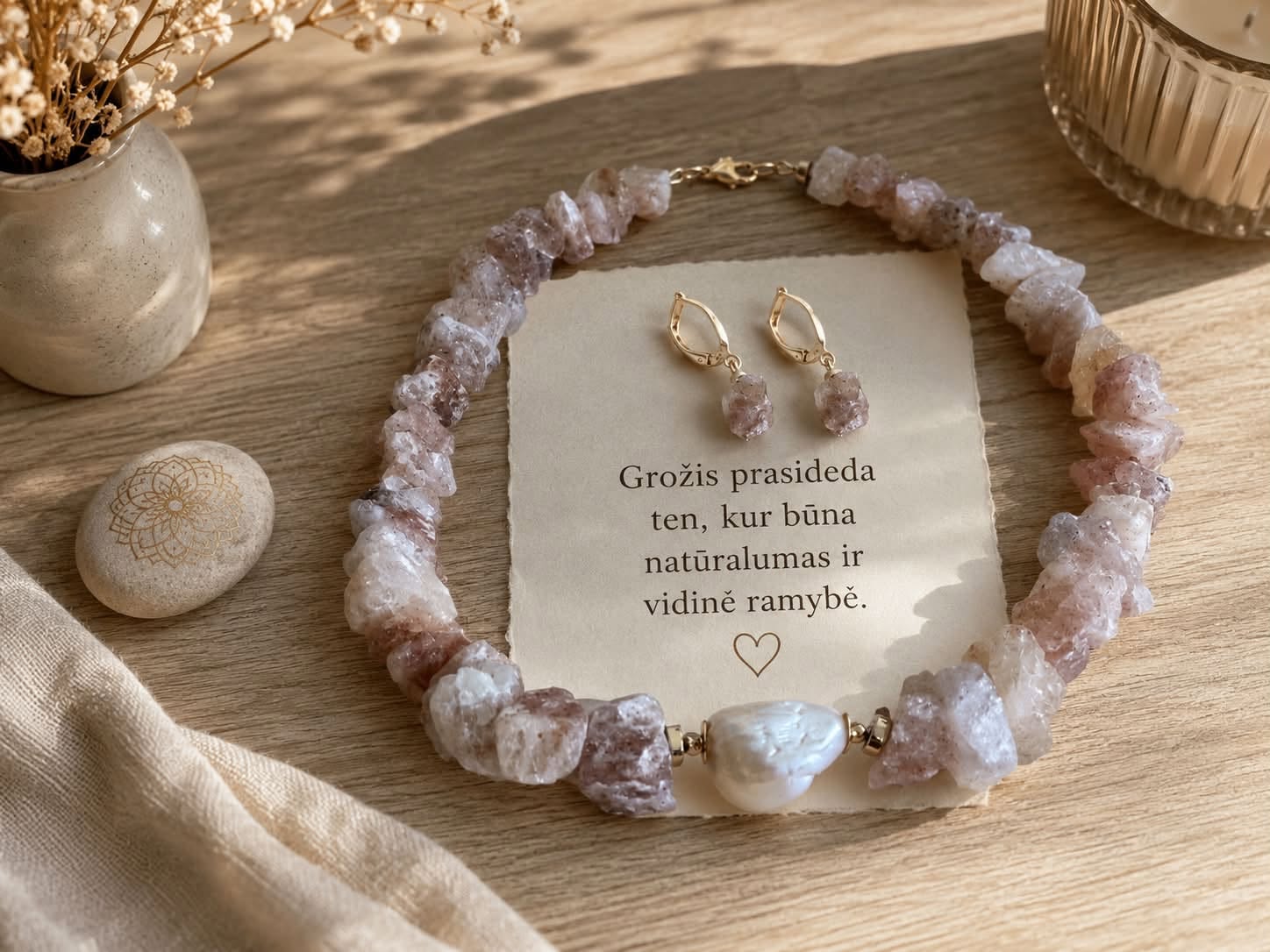 Rausvų akmenų vėrinys ir auskarai ant medinio paviršiaus